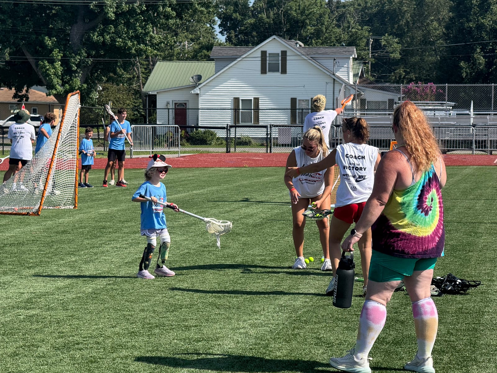 Gwen holding a lacrosse stick on the field during the Little League program at NubAbility All Sports Camp