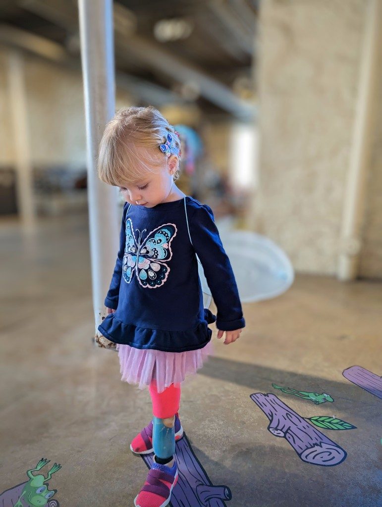 Gwen standing and looking down at her feet while wearing her second set of prosthetics