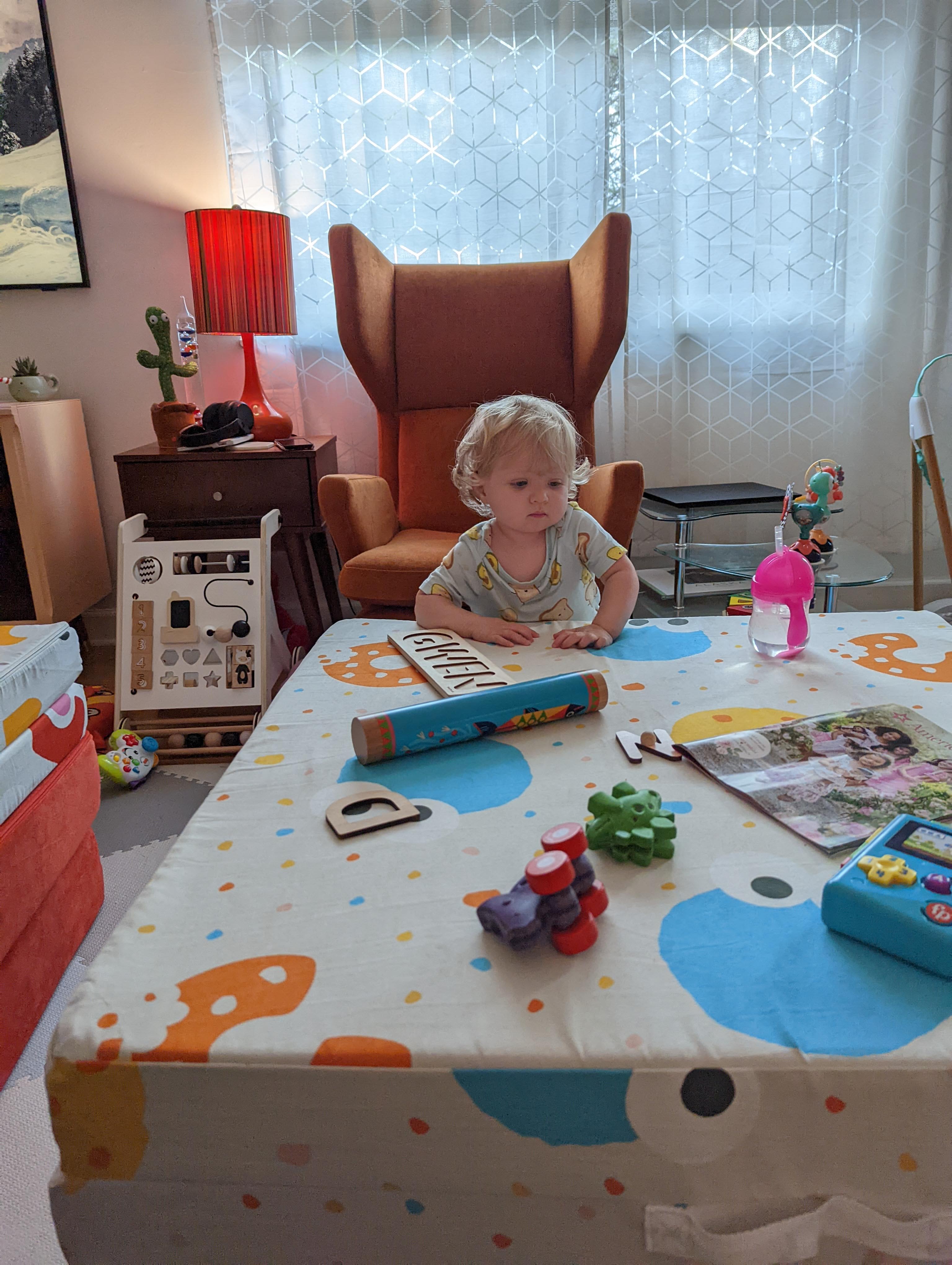Gwen standing next to her Nugget play couch with toys on top